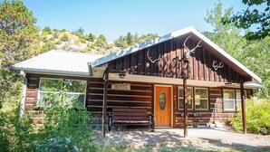 A rustic log cabin with a prominent elk head mounted on the front, labeled "EMIGRANT GULCH."