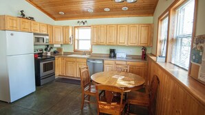 A kitchen with wooden cabinets, a refrigerator, stove, microwave, sink, and a dining table with chairs.