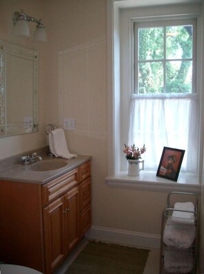 Long bathroom with tiled shower stall and in unit washer/dryer (not shown)