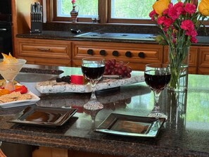 A kitchen counter with a marble top, a glass vase with flowers, and a wine glass.