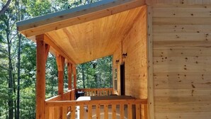 A wooden cabin with a porch, surrounded by trees. - Private Ravine View Luxury Amish-Built Cabin "The Frontier" (Genoa)