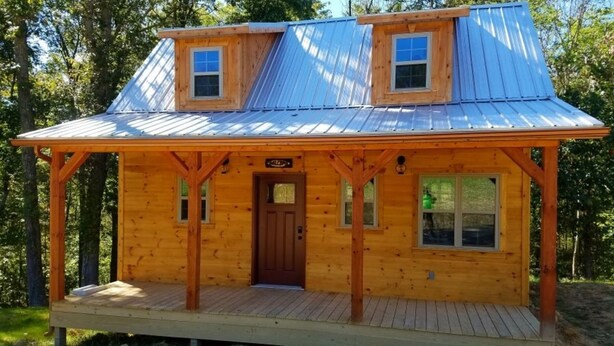A wooden cabin with a porch, two windows, and a door. - Private Ravine View Luxury Amish-Built Cabin "The Frontier" (Genoa)