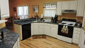 A kitchen with white cabinets, a black stove, and a wooden floor. - RiverFront, WI-FI /Cell,  Pet Friendly, Folk School (Murphy)