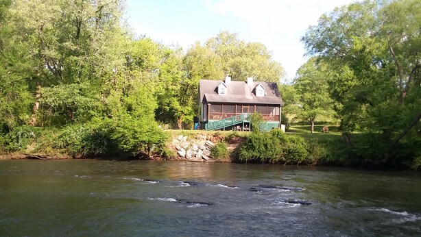 A house with a green deck and a stone wall by a river. - RiverFront, WI-FI /Cell,  Pet Friendly, Folk School (Murphy)