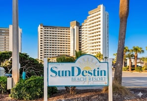 Schild für SunDestin Beach Resort, im Hintergrund hohe Gebäude sichtbar.