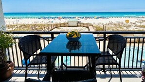 Un balcón con mesa y sillas, un frutero y vista a la playa.
