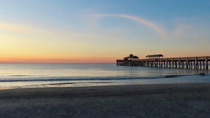 A pier extending into calm waters with a beach in the foreground. - Airy & Bright Folly Condo; Close to Everything (Folly Beach)