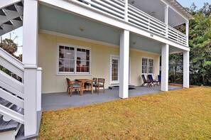 A covered porch with a dining table and chairs, a staircase, and a number '114' on the wall.
