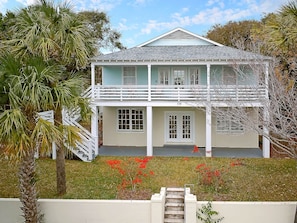A two-story house with a balcony, a front porch, and a staircase leading to the entrance.