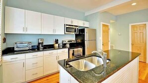 A modern kitchen with white cabinets, a stainless steel sink, a microwave, and a stove. - Airy & Bright Folly Condo; Close to Everything (Folly Beach)
