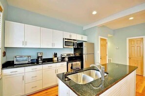 A modern kitchen with white cabinets, a stainless steel sink, a microwave, and a stove. - Airy & Bright Folly Condo; Close to Everything (Folly Beach)