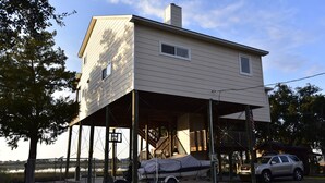 A two-story house with a covered porch and a boat dock. - WATERFRONT Home  - Dolphins, Sunsets, Fishing, Kayaks, Canoe, Wildlife (Crawfordville)