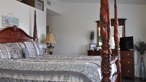 A bedroom with a four-poster bed, a television on a dresser, and a potted plant. - WATERFRONT Home  - Dolphins, Sunsets, Fishing, Kayaks, Canoe, Wildlife (Crawfordville)