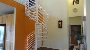 A spiral staircase with white railings and string lights, leading to an upper level. - WATERFRONT Home  - Dolphins, Sunsets, Fishing, Kayaks, Canoe, Wildlife (Crawfordville)
