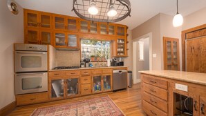 Una cucina con mobili in legno, elettrodomestici in acciaio inossidabile e un tappeto decorato.