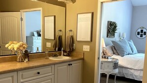 Un baño con un espejo grande, un lavabo y un mueble con cajones. Hay una alfombra decorativa en el suelo.