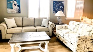 A living room with a beige sofa, a patterned sofa, a coffee table, and a lamp. - Pet-Friendly,No Cleaning Fees, 2BR/2BA Condo Near Pool in Bethany Bay - Sleeps 6 (Ocean View)