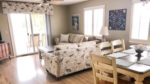 A cozy living room with a sofa, a dining table with chairs, and a ceiling fan. - Pet-Friendly,No Cleaning Fees, 2BR/2BA Condo Near Pool in Bethany Bay - Sleeps 6 (Ocean View)
