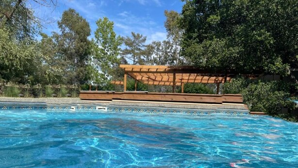 Une piscine aux eaux cristallines, dotée d’une terrasse en bois et d’une pergola.