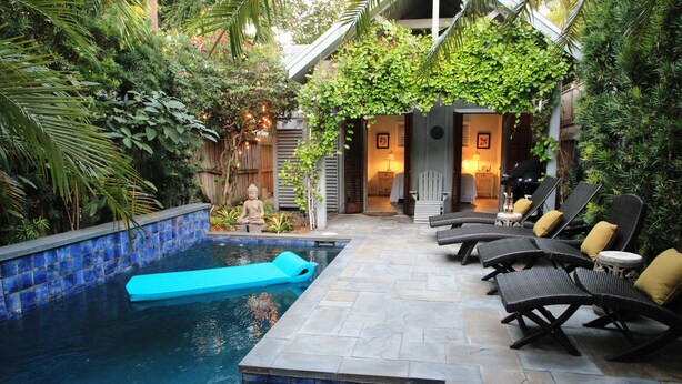 Un área de piscina privada con sillones de descanso y una pequeña estatua de Buda.