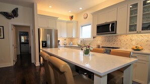 Cocina moderna con armarios blancos, una isla central y un microondas.