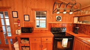 Una cocina de madera con estufa, microondas y armarios de madera.