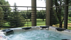 A hot tub with a view of a grassy area and trees.