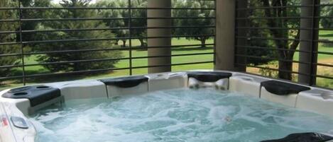A hot tub with a view of a grassy area and trees.