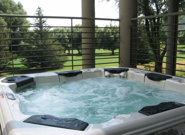 A hot tub with a view of a grassy area and trees.