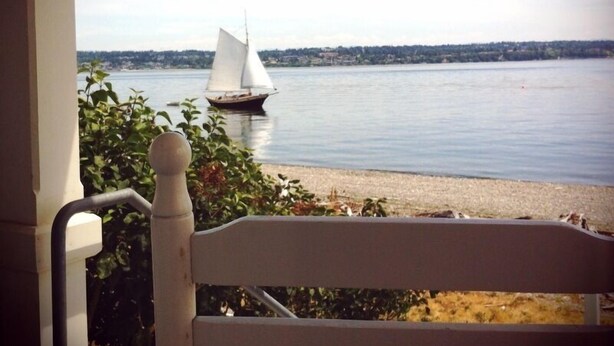 A view of a calm lake with a sailboat in the distance.