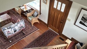 A staircase with wooden railings leading to a living area with a sofa, cushions, and a patterned rug.