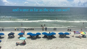 Een strand met parasols en mensen die van het water genieten.