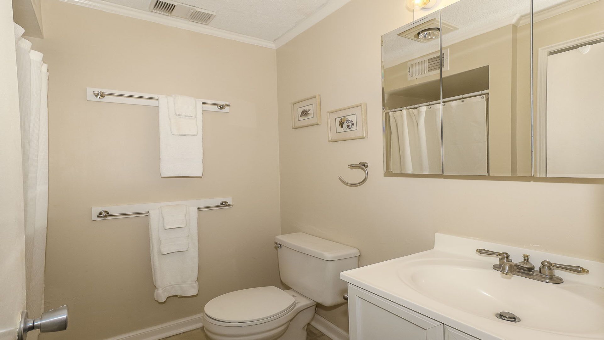 A small, clean bathroom with a toilet, sink, and towel rack.