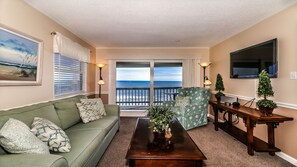 Relax in this ocean-view living room with a sofa, armchair, and flat-screen TV.