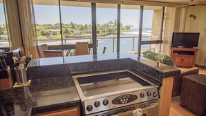 A kitchen with a large island, a stove, and a view of the ocean.