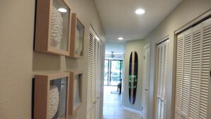 Un couloir orné de tableaux encadrés, doté d’un ventilateur de plafond et de portes coulissantes.