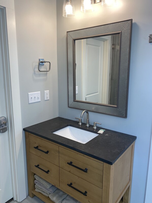 A bathroom with a white sink, wooden vanity, and a large mirror. - Luxurious Lakefront Retreat (Northport)