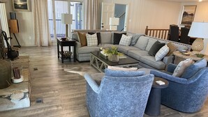 A spacious living room with a grey sectional sofa, blue armchairs, and a coffee table. - Luxurious Lakefront Retreat (Northport)