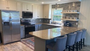 A modern kitchen with a large island, stainless steel appliances, and a stone backsplash. - Luxurious Lakefront Retreat (Northport)