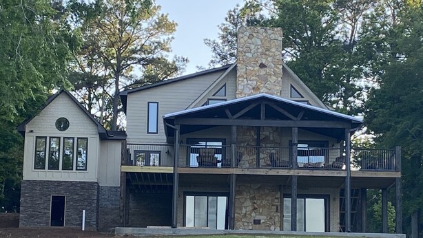 A two-story house with a stone chimney, a balcony, and a covered porch. - Luxurious Lakefront Retreat (Northport)
