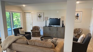 A living room with a sofa, armchairs, a coffee table, and a TV on a wooden cabinet. - Luxurious Lakefront Retreat (Northport)