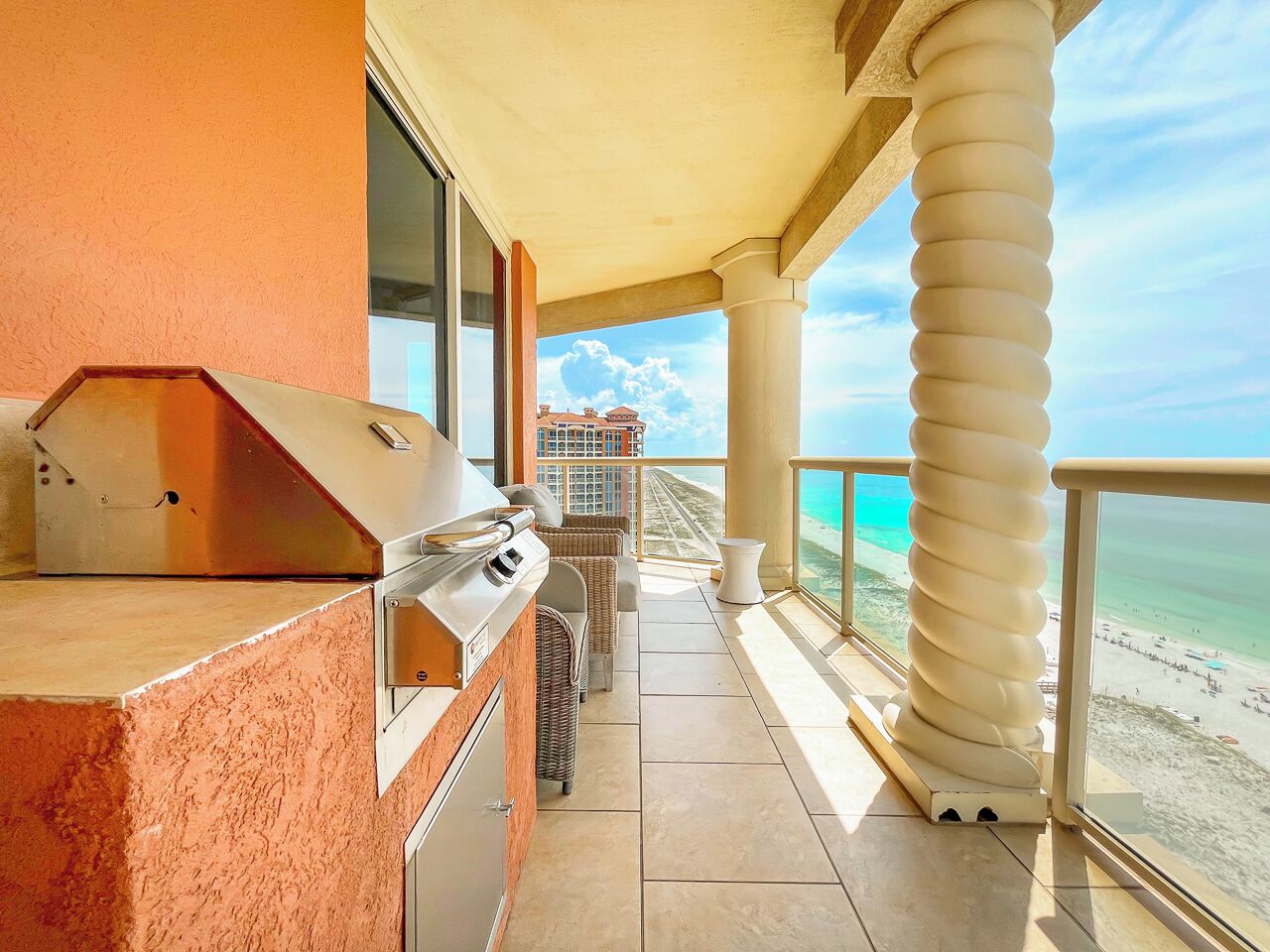Ein Balkon mit Grill, Korbmöbeln und Blick auf den Strand.