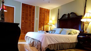Ein Schlafzimmer mit einem großen Bett, einem Holzkopfteil, zwei Nachttischlampen und einer hölzernen Kommode.