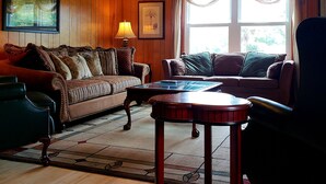 Ein Wohnzimmer mit Deckenventilator, einer Couch, einem Couchtisch und einem Sessel.