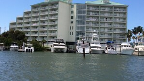 Un hotel de varios pisos con balcones, una marina con varios barcos y un cielo despejado.