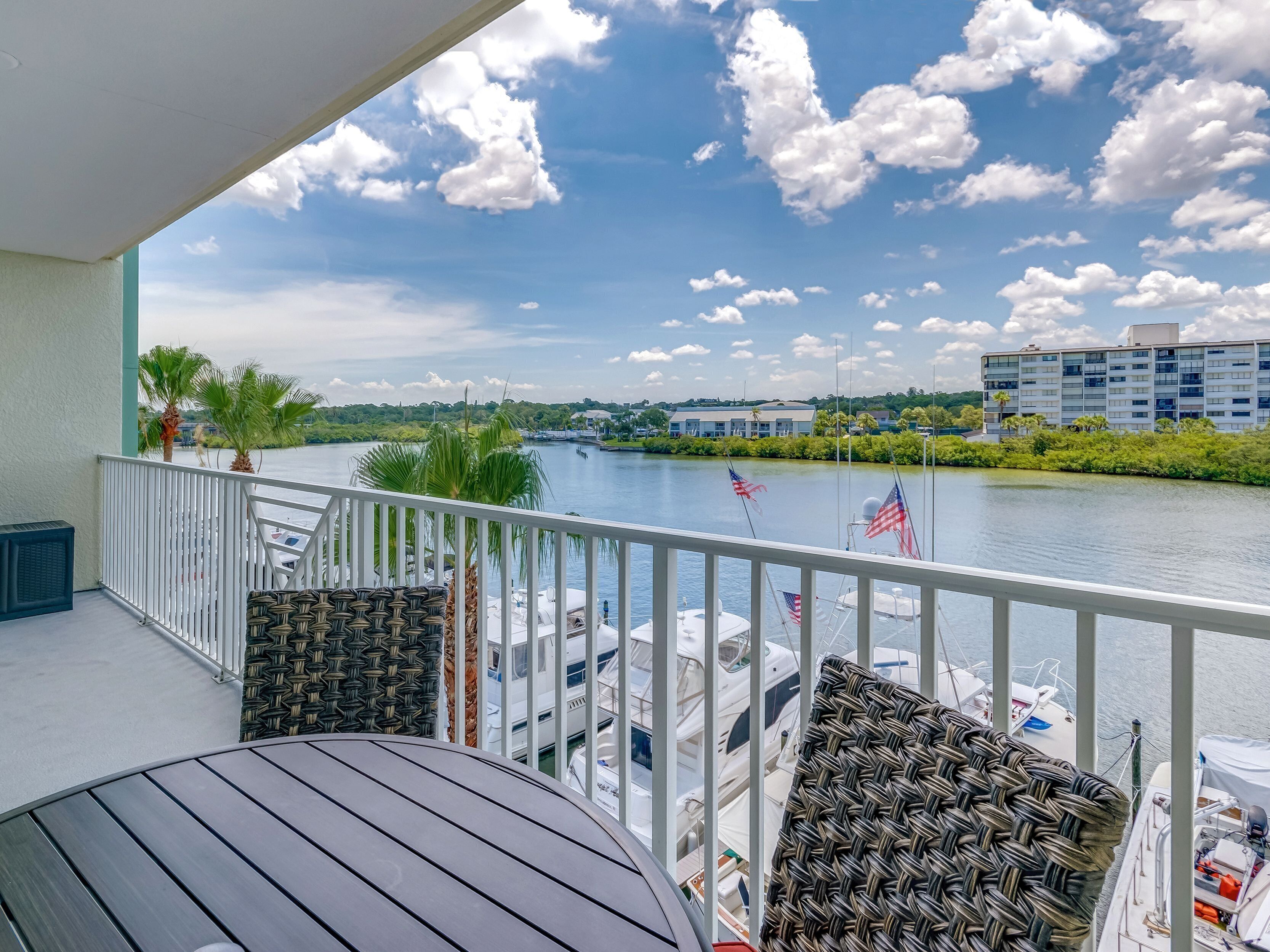 Un balcon avec vue sur une rivière, des bateaux et un bâtiment situé de l’autre côté.