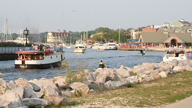 A marina with boats docked, a clock tower, and a building with a red archway.