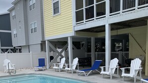 Une piscine avec des chaises longues et un espace patio couvert.