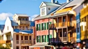 A street with colorful buildings, a clear sky, and a small boat in the water.