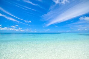 A clear blue sky over a calm sea with a pier extending into the water.